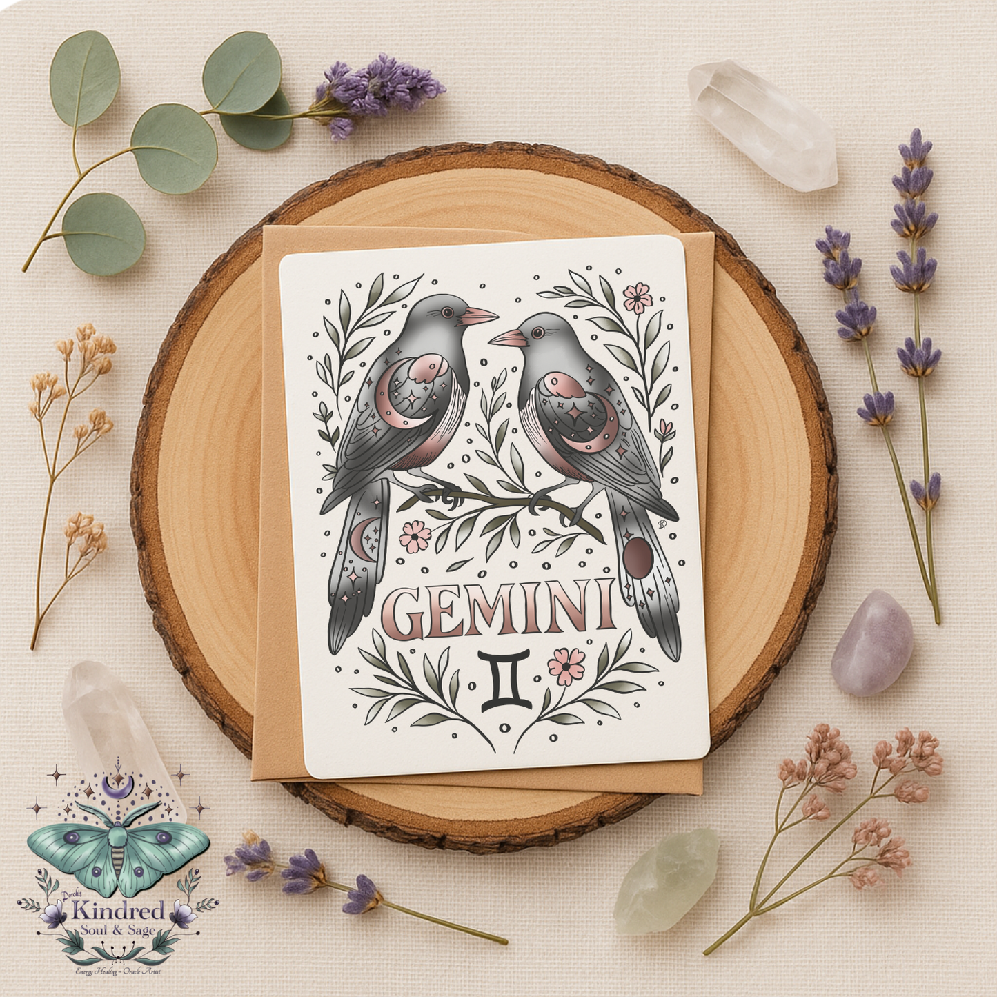 Greeting card with Gemini zodiac design on a wooden round surface with flowers and crystals.